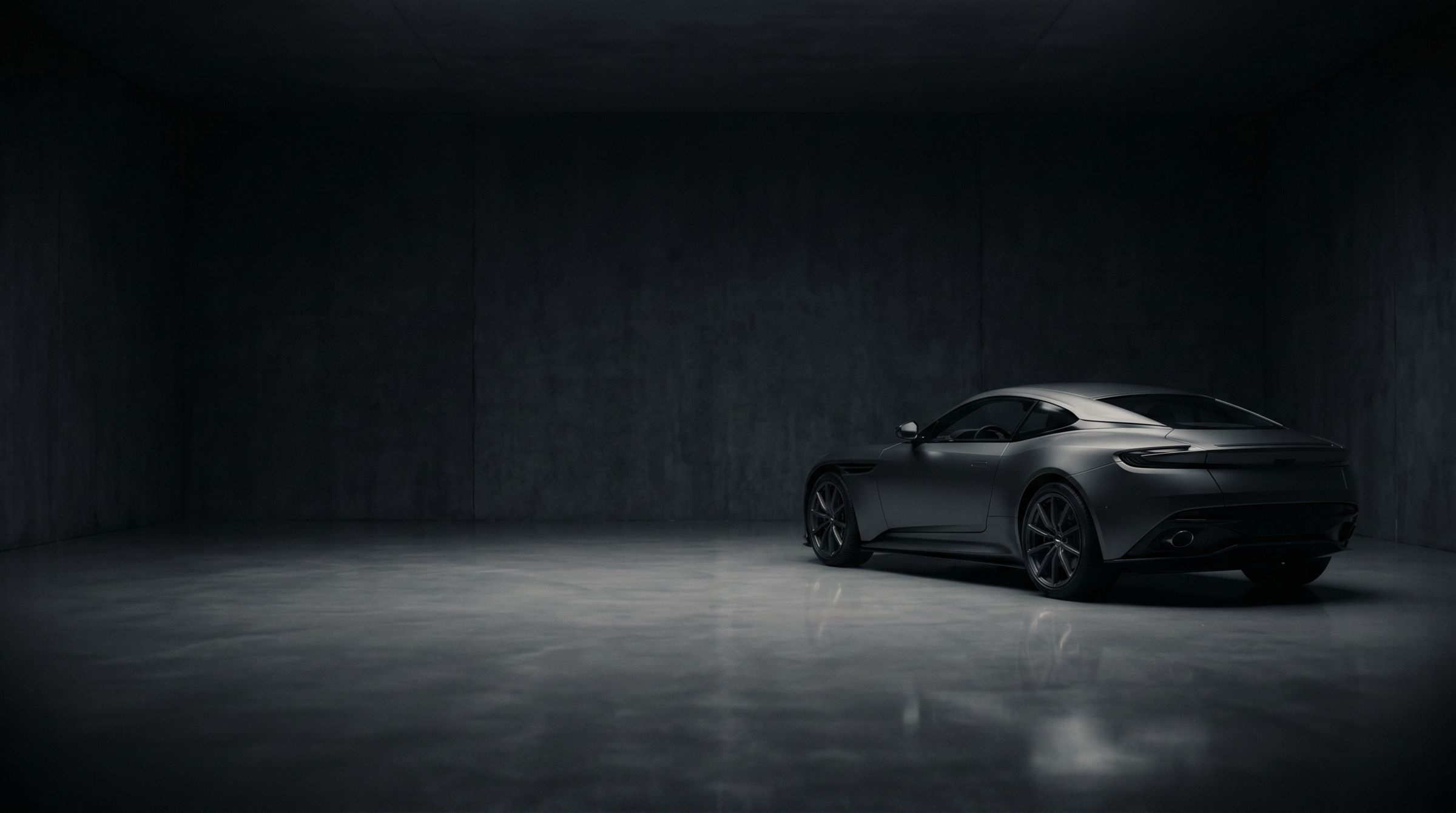 A graphite European coupé at rest in a discreet, low-lit private storage space.